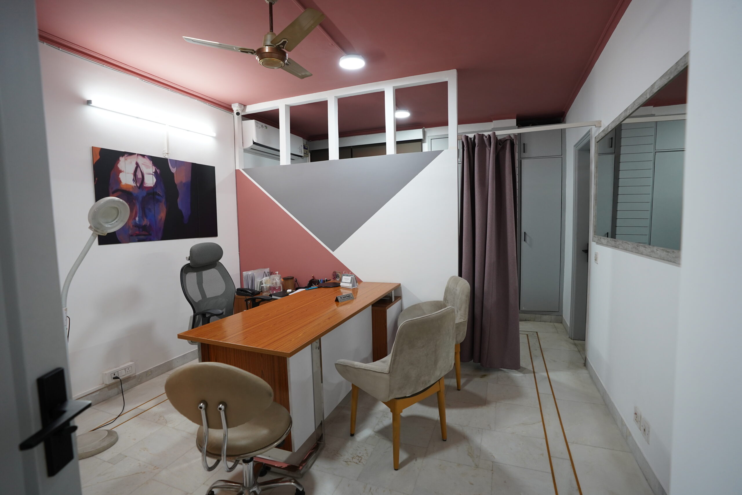 Dr. Jyoti Clinic consultation room with wooden desk and geometric accent wall