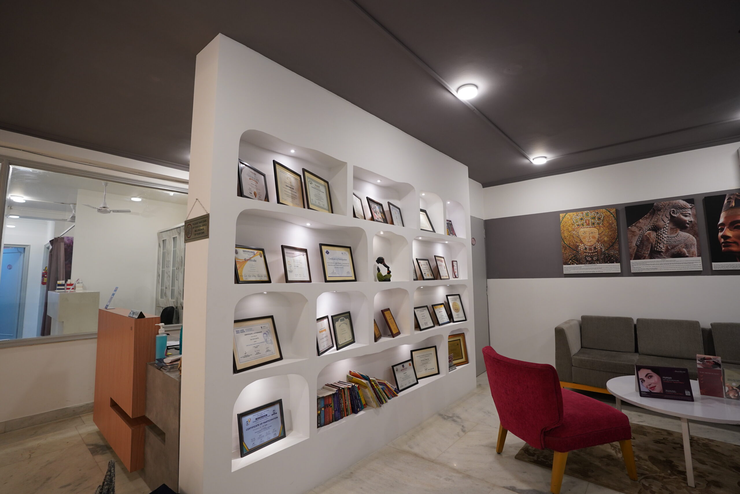 Dr. Jyoti Clinic waiting area with certificate display wall and red accent chair