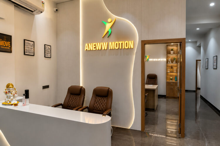 Illuminated Aneww Motion branded signage above the reception seating area with framed anatomy posters in a physiotherapy clinic interior designed by Nail & Hammer
