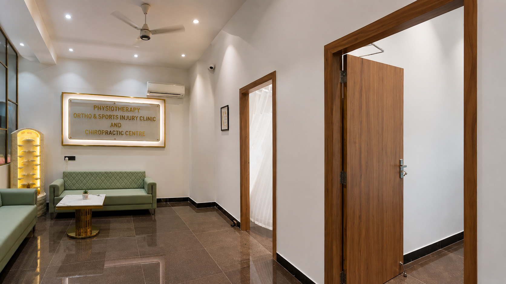 Physiotherapy Clinic Waiting Area & Treatment Room Corridor – Nail & Hammer Waiting area with mint-green sofas and a backlit clinic name board beside a corridor leading to treatment rooms with wooden doors in a physiotherapy clinic interior designed by Nail & Hammer
